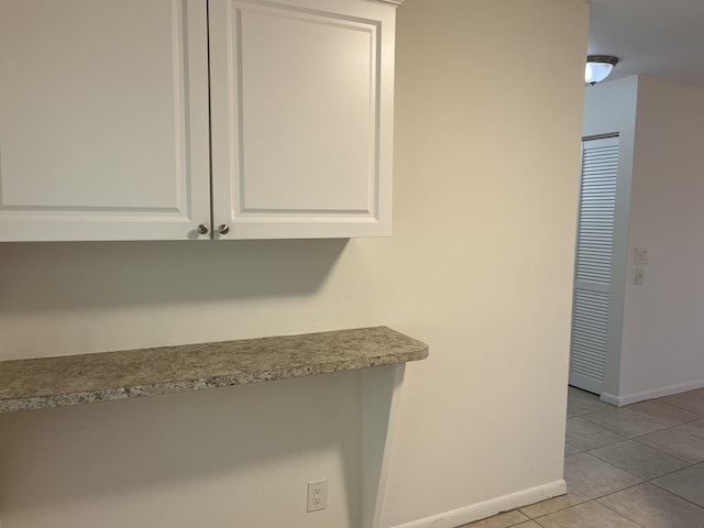 interior space with light tile patterned floors, baseboards, and white cabinetry