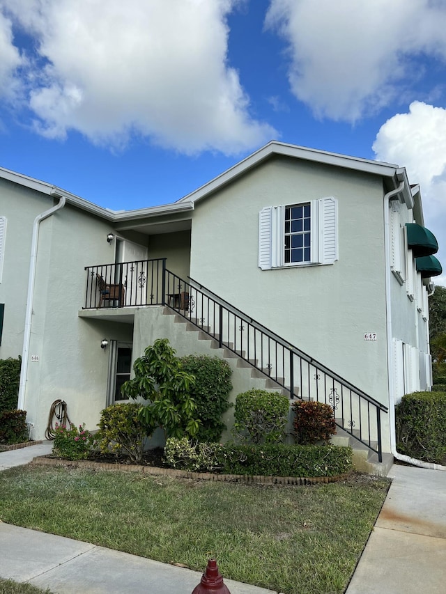 view of property exterior featuring stairway, a balcony, and stucco siding