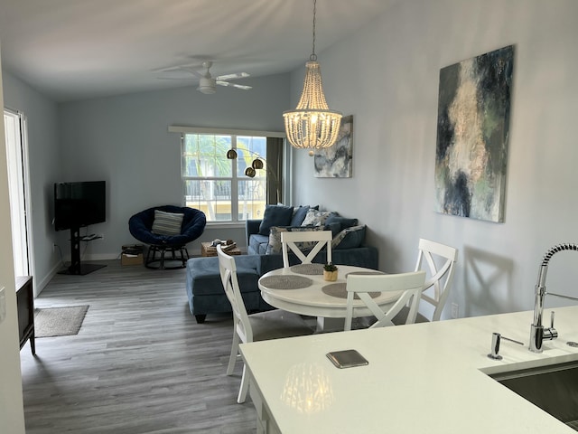 dining area featuring lofted ceiling, baseboards, wood finished floors, and ceiling fan with notable chandelier