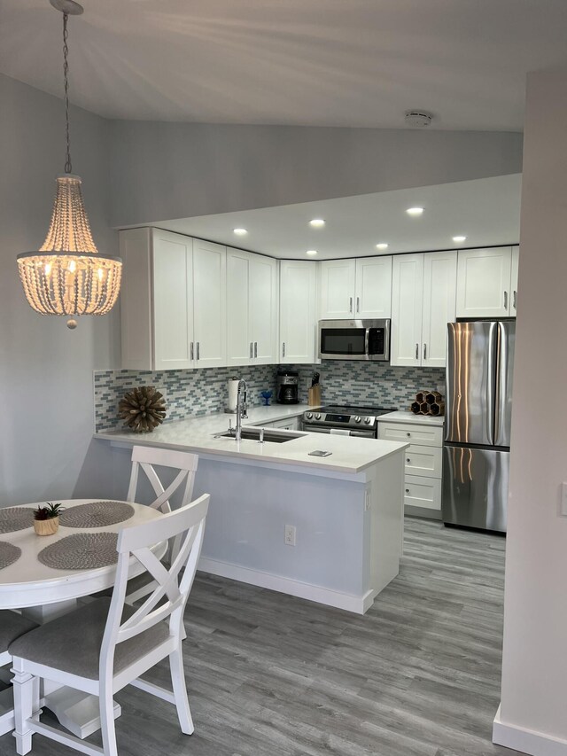 kitchen with lofted ceiling, appliances with stainless steel finishes, light countertops, and a sink