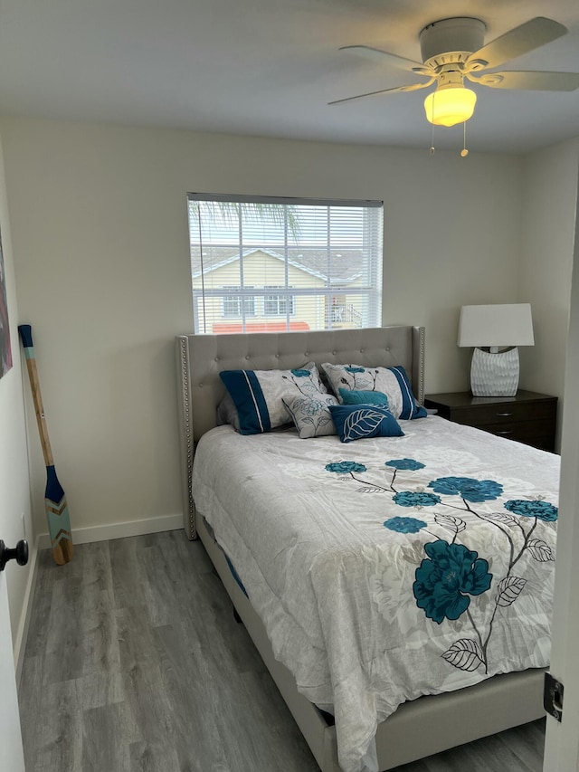 bedroom with ceiling fan, wood finished floors, and baseboards