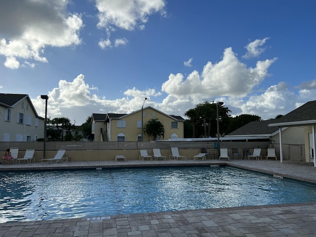 community pool with a patio area and fence