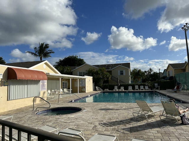 pool featuring a patio, fence, and a hot tub