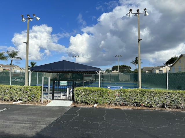 view of home's community featuring a tennis court and fence