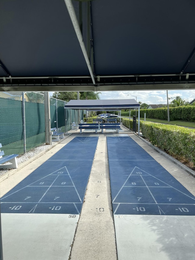 view of community featuring fence and shuffleboard