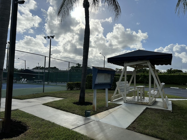 surrounding community with a tennis court and fence