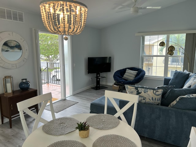 living area with light wood finished floors, baseboards, visible vents, vaulted ceiling, and ceiling fan with notable chandelier