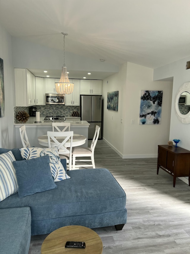 living room featuring light wood-type flooring, baseboards, and a notable chandelier