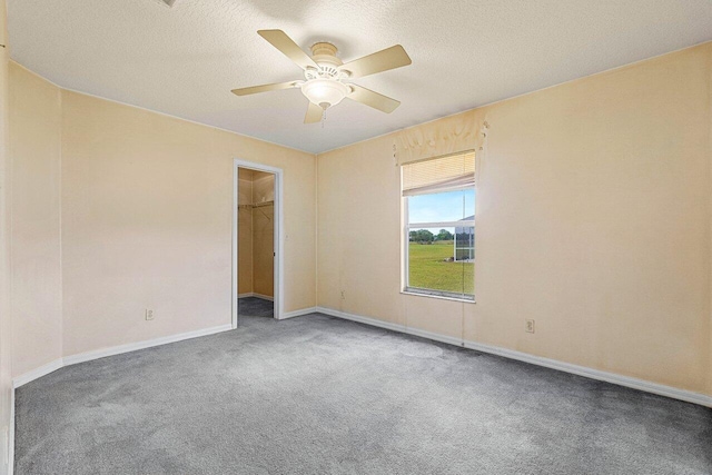 empty room with carpet floors, ceiling fan, baseboards, and a textured ceiling