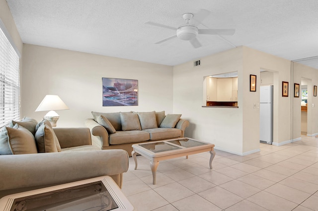 living area with a ceiling fan, light tile patterned floors, visible vents, and a textured ceiling