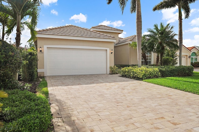 view of front of property with an attached garage, a tile roof, decorative driveway, and stucco siding