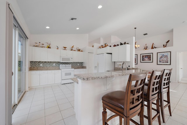 3190 SE Carrick Green Ct, Port Saint Lucie, FL 34952 - kitchen featuring white appliances, light tile patterned flooring, a peninsula, tasteful backsplash, and light stone countertops