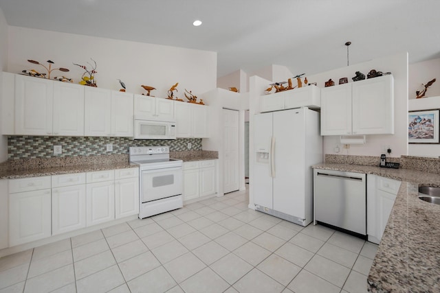 3190 SE Carrick Green Ct, Port Saint Lucie, FL 34952 - kitchen with white appliances, tasteful backsplash, white cabinets, light stone counters, and light tile patterned floors