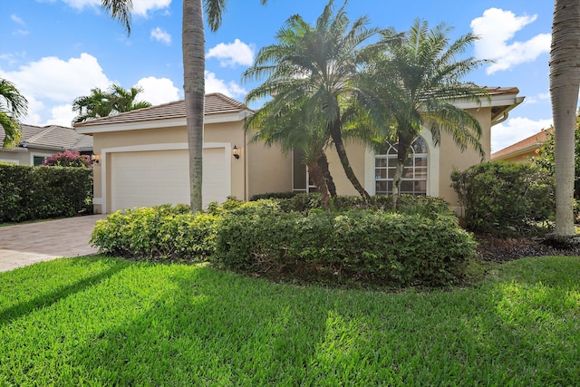3190 SE Carrick Green Ct, Port Saint Lucie, FL 34952 - view of front facade featuring stucco siding, an attached garage, driveway, a front lawn, and a tile roof
