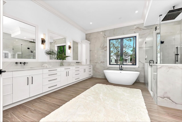 full bathroom featuring crown molding, tile walls, double vanity, a shower stall, and a freestanding tub