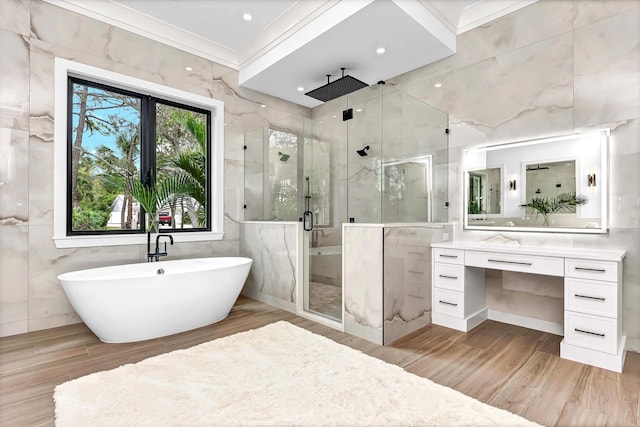 bathroom with ornamental molding, vanity, a freestanding tub, a shower stall, and tile walls