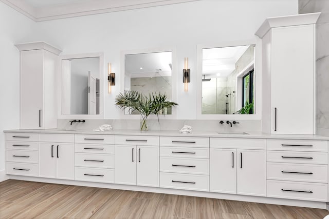 bathroom featuring a sink, double vanity, wood finished floors, and a marble finish shower