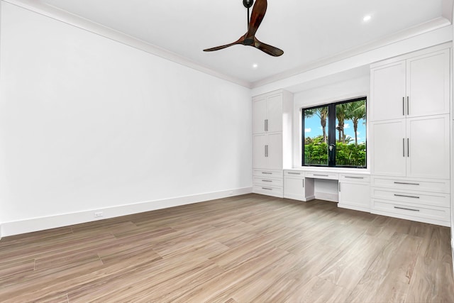 unfurnished bedroom featuring a ceiling fan, baseboards, light wood finished floors, built in desk, and crown molding