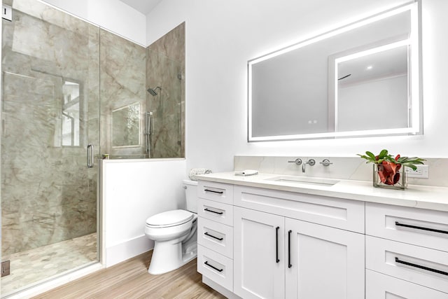 bathroom with toilet, a shower stall, wood finished floors, and vanity