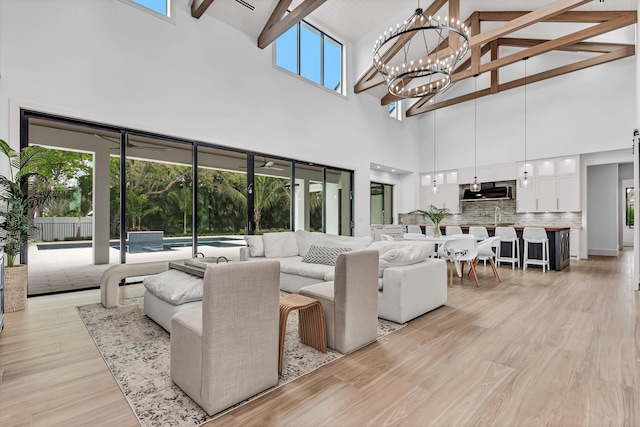 living area with lofted ceiling with beams, an inviting chandelier, and light wood-style flooring