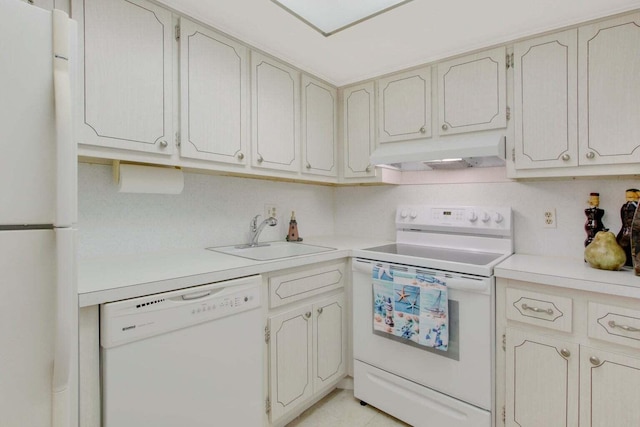 kitchen with white appliances, under cabinet range hood, light countertops, and a sink