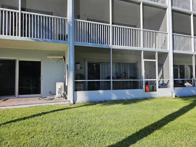 rear view of house featuring a lawn and stucco siding