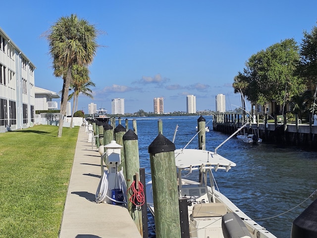 dock area featuring a water view, a view of city, and a yard