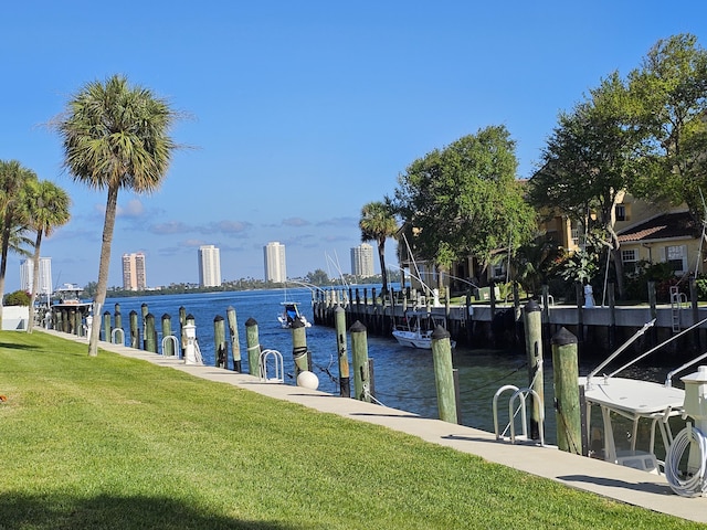 view of dock with a water view, a city view, and a yard