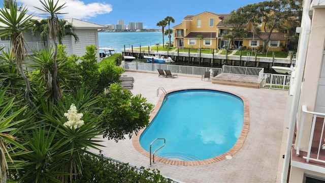 pool with a patio area, a water view, and fence