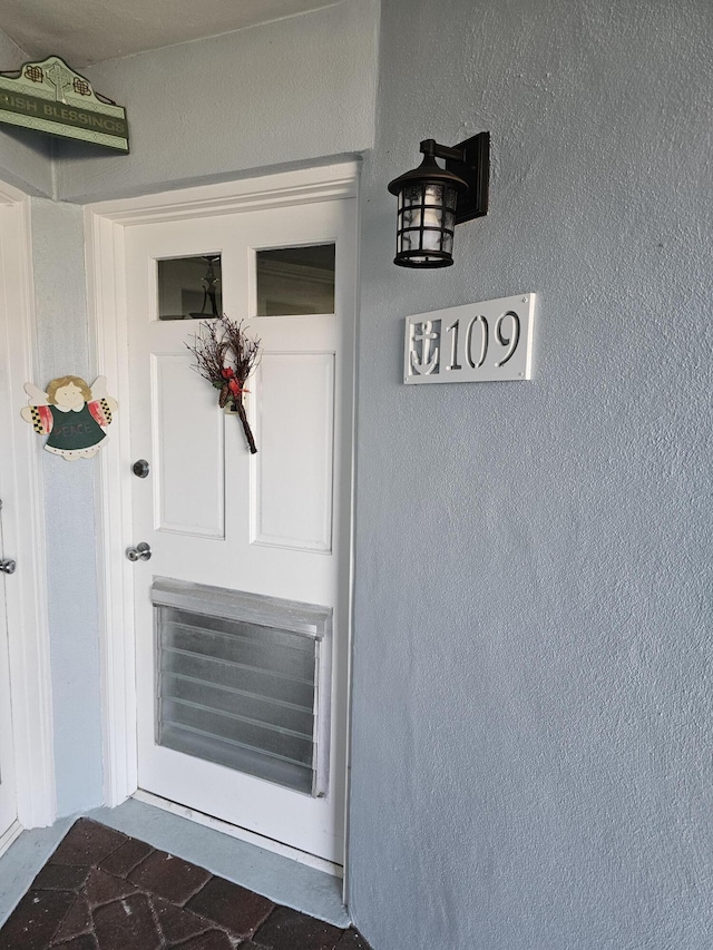 doorway to property featuring stucco siding