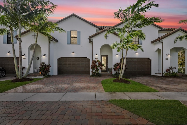 mediterranean / spanish-style house with a tiled roof, decorative driveway, and stucco siding