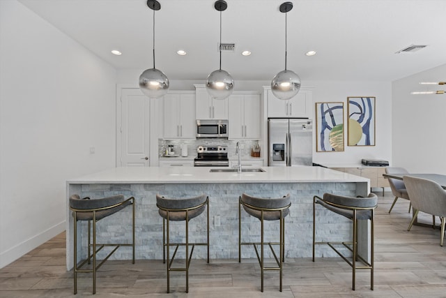 kitchen with a sink, visible vents, white cabinetry, appliances with stainless steel finishes, and decorative backsplash