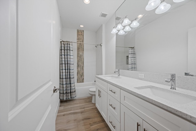 bathroom featuring double vanity, visible vents, a sink, and wood finished floors