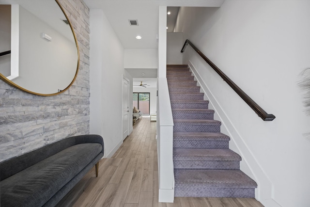 staircase featuring ceiling fan, wood finished floors, and visible vents