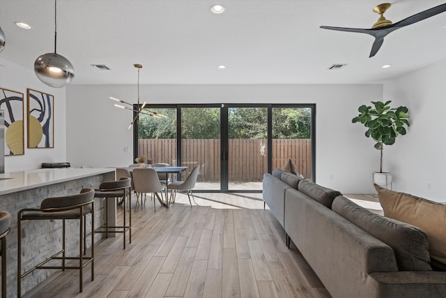 living room with light wood-type flooring, visible vents, and recessed lighting