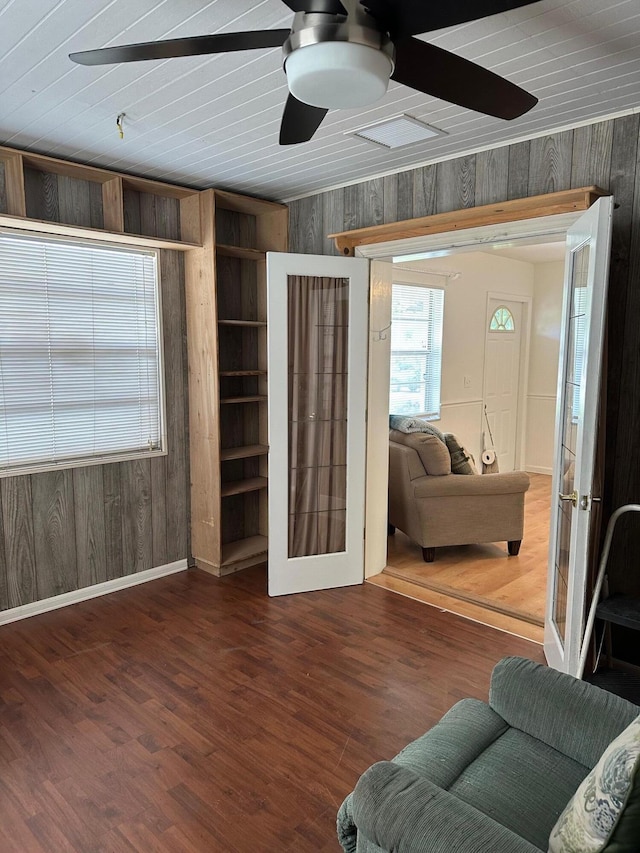 living area featuring french doors, ceiling fan, wooden walls, wood finished floors, and baseboards