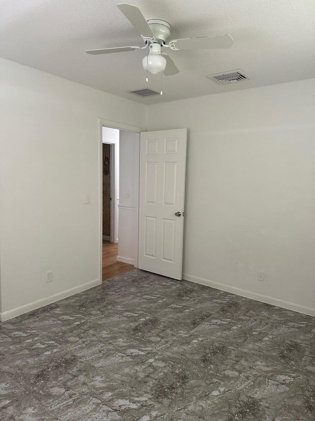 empty room featuring visible vents, ceiling fan, a textured ceiling, and baseboards