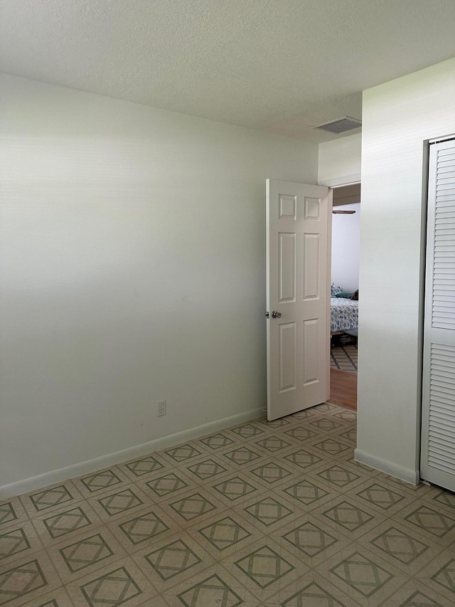 spare room with visible vents, a textured ceiling, and baseboards