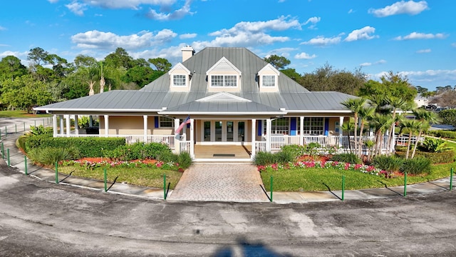 view of front of property with metal roof, a porch, and a chimney