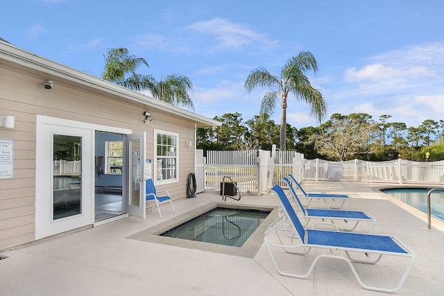 pool featuring a patio, fence, and a hot tub