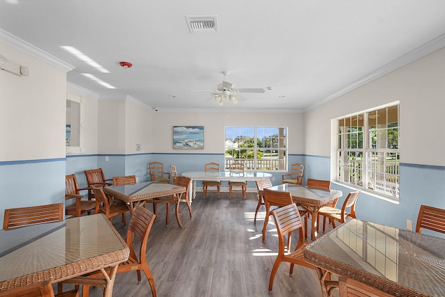 dining area featuring a wainscoted wall, crown molding, visible vents, and wood finished floors