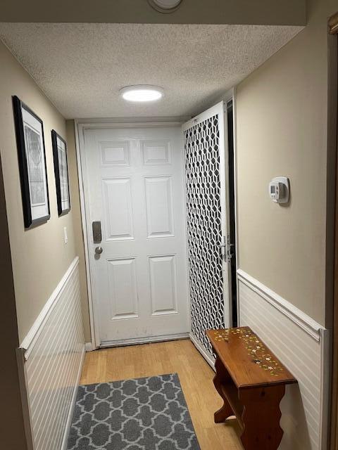 2424 N Federal Hwy Unit 106, Boynton Beach, FL 33435 - doorway to outside featuring light wood-type flooring, baseboards, and a textured ceiling