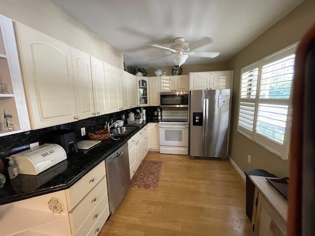 2424 N Federal Hwy Unit 106, Boynton Beach, FL 33435 - kitchen featuring a ceiling fan, a sink, decorative backsplash, light wood finished floors, and appliances with stainless steel finishes