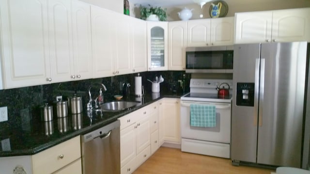 2424 N Federal Hwy Unit 106, Boynton Beach, FL 33435 - kitchen featuring white cabinets, stainless steel appliances, dark countertops, a sink, and tasteful backsplash