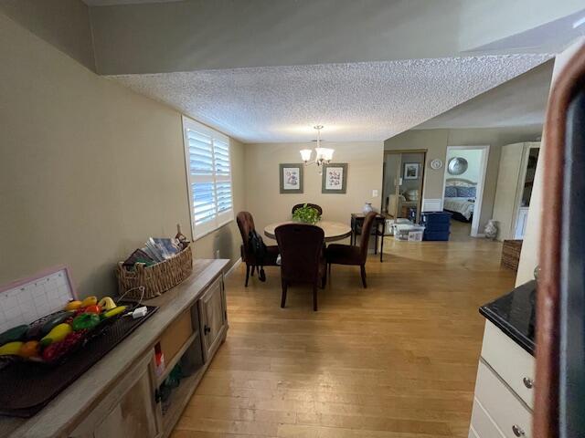 2424 N Federal Hwy Unit 106, Boynton Beach, FL 33435 - dining room featuring a chandelier, light wood-type flooring, and a textured ceiling