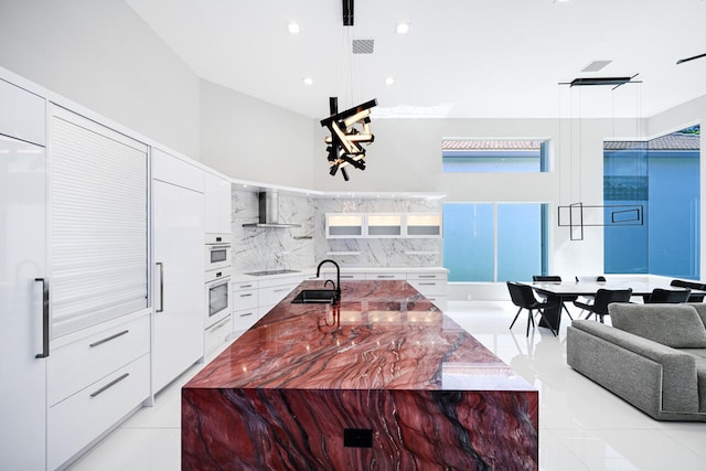 kitchen with wall chimney exhaust hood, modern cabinets, black electric stovetop, and a sink