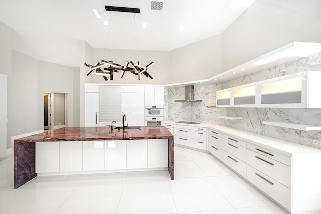 kitchen featuring tasteful backsplash, visible vents, black electric cooktop, wall chimney range hood, and a sink