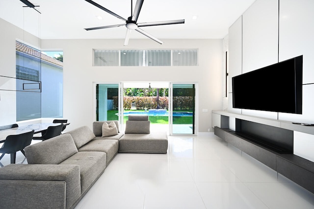 living room featuring ceiling fan, a high ceiling, and tile patterned flooring