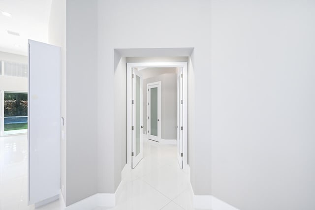 corridor featuring light tile patterned floors and baseboards