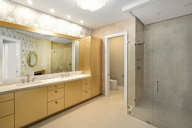 bathroom featuring a sink, a shower stall, and wallpapered walls